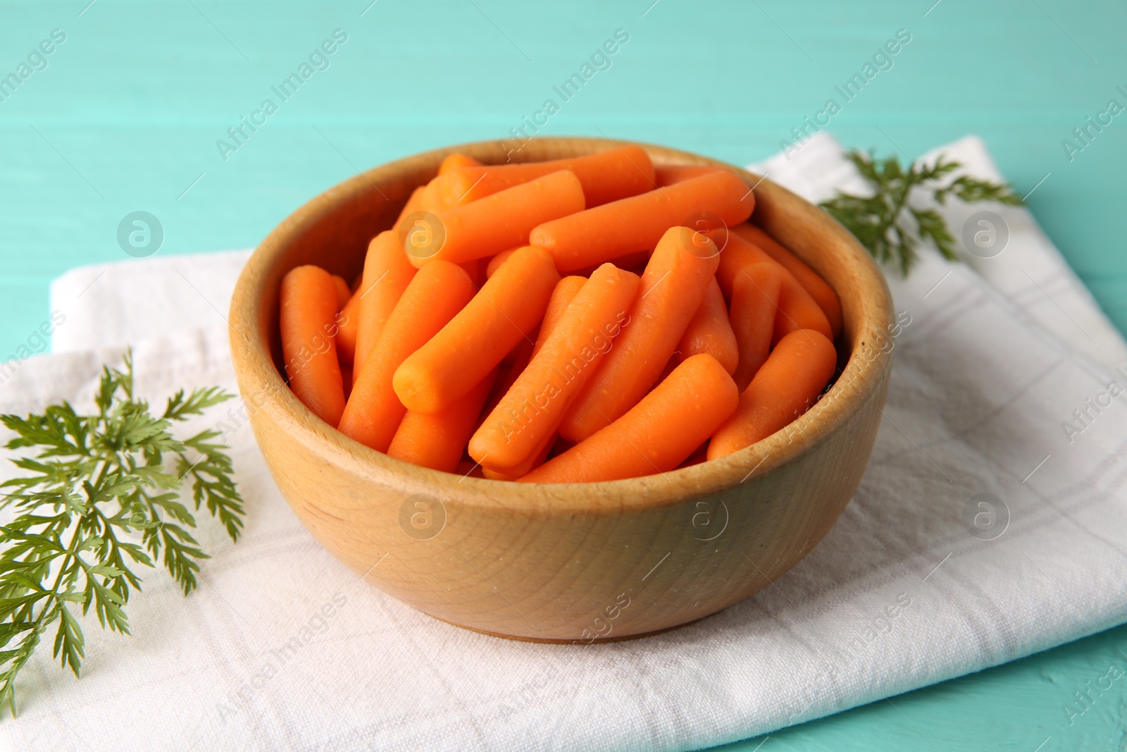 Photo of Baby carrots and green leaves on light blue wooden table