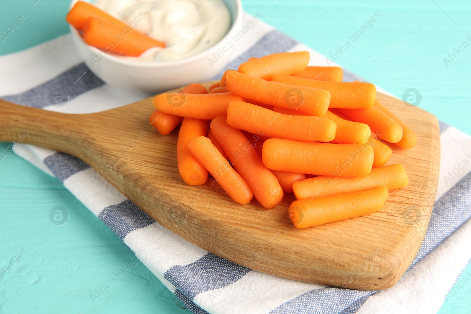 Photo of Baby carrots and sauce on light blue wooden table