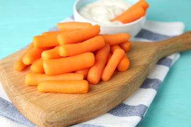 Photo of Baby carrots and sauce on light blue wooden table