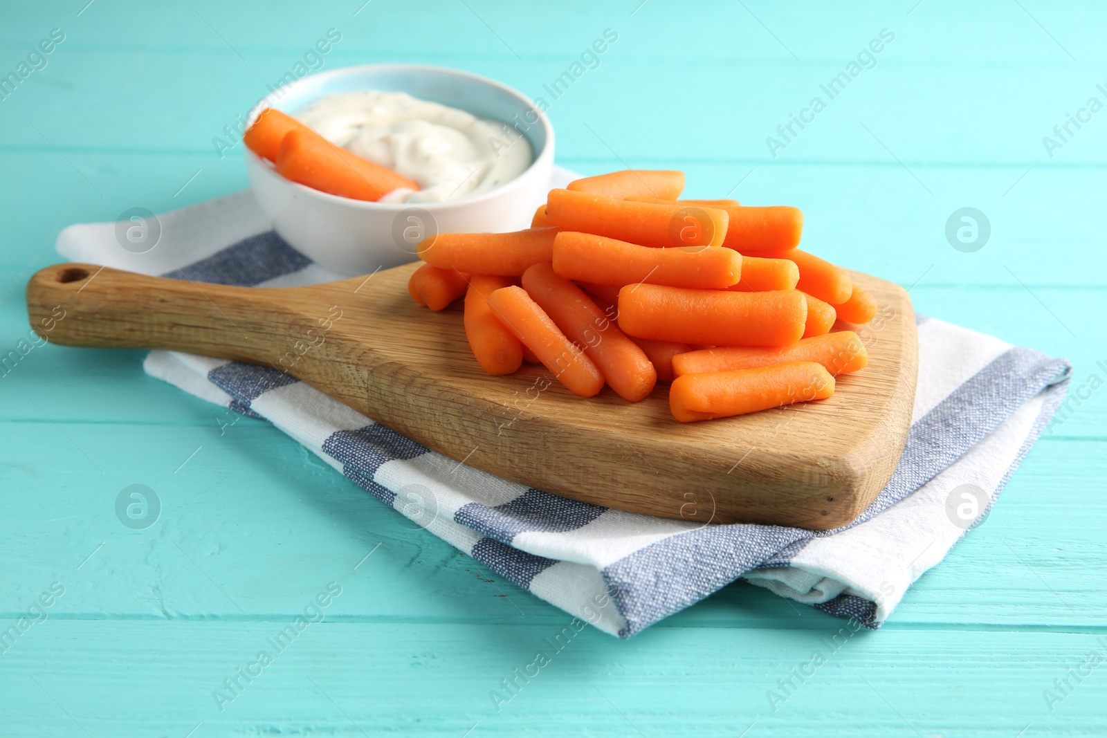 Photo of Baby carrots and sauce on light blue wooden table