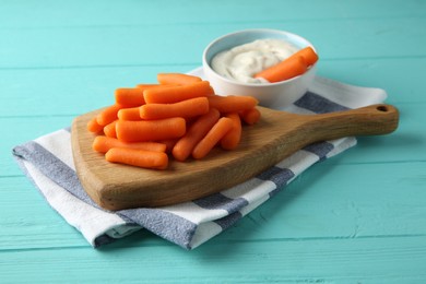 Photo of Baby carrots and sauce on light blue wooden table