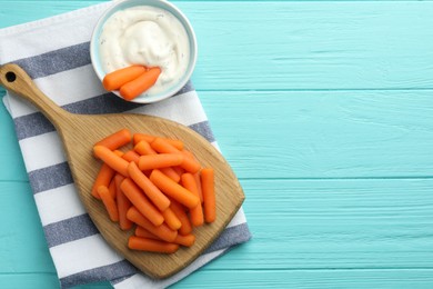 Photo of Baby carrots and sauce on light blue wooden table, top view. Space for text