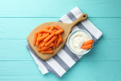 Photo of Baby carrots and sauce on light blue wooden table, top view