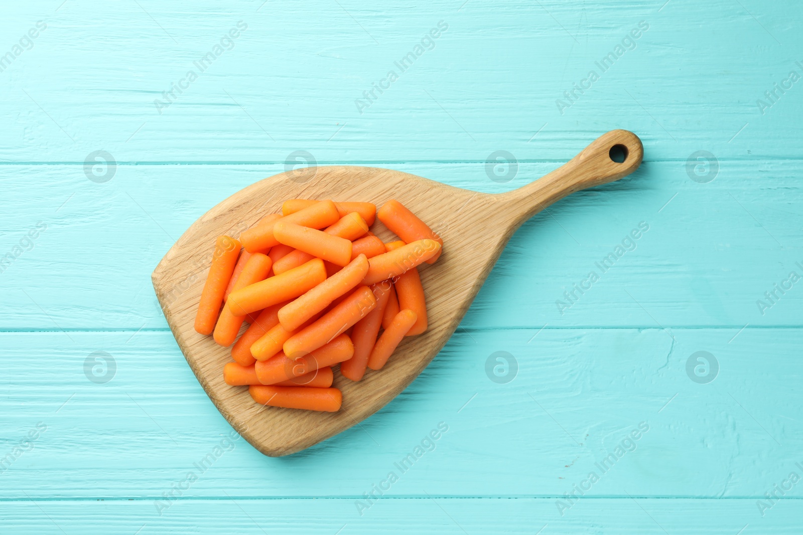 Photo of Baby carrots on light blue wooden table, top view