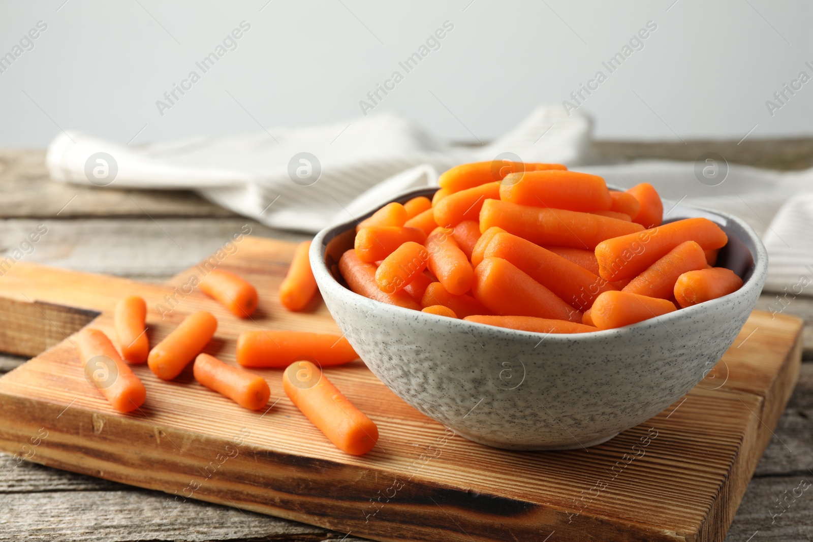 Photo of Baby carrots in bowl on wooden table