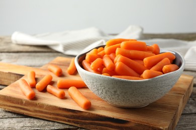 Baby carrots in bowl on wooden table