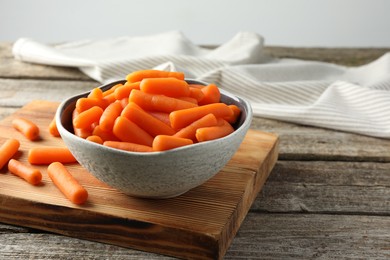 Baby carrots in bowl on wooden table