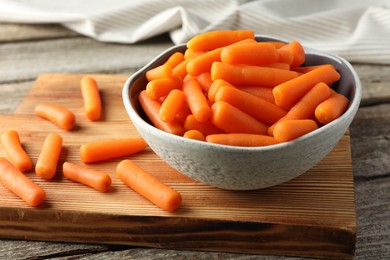 Photo of Baby carrots in bowl on wooden table