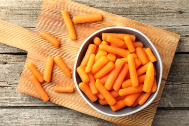 Photo of Baby carrots in bowl on wooden table, top view