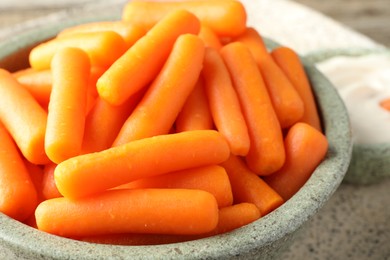 Photo of Baby carrots in bowl on table, closeup