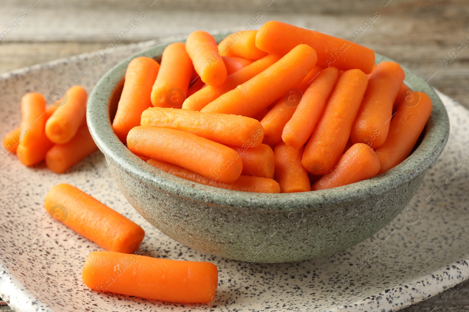 Photo of Baby carrots in bowl on table, closeup