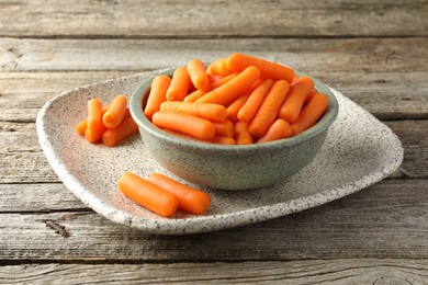 Photo of Baby carrots in bowl on wooden table