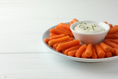 Baby carrots and sauce on white wooden table, space for text