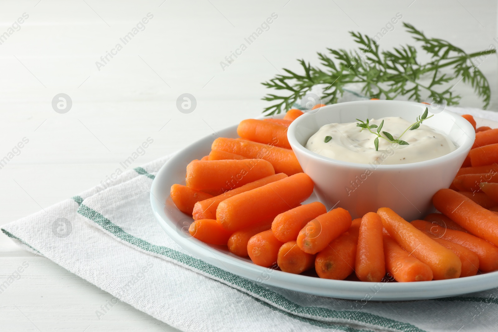 Photo of Baby carrots, sauce and green leaf on white wooden table. Space for text