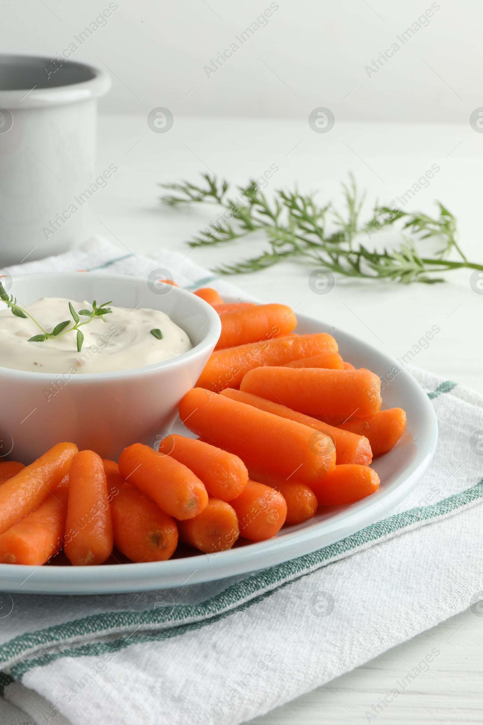 Photo of Baby carrots, sauce and green leaf on white wooden table