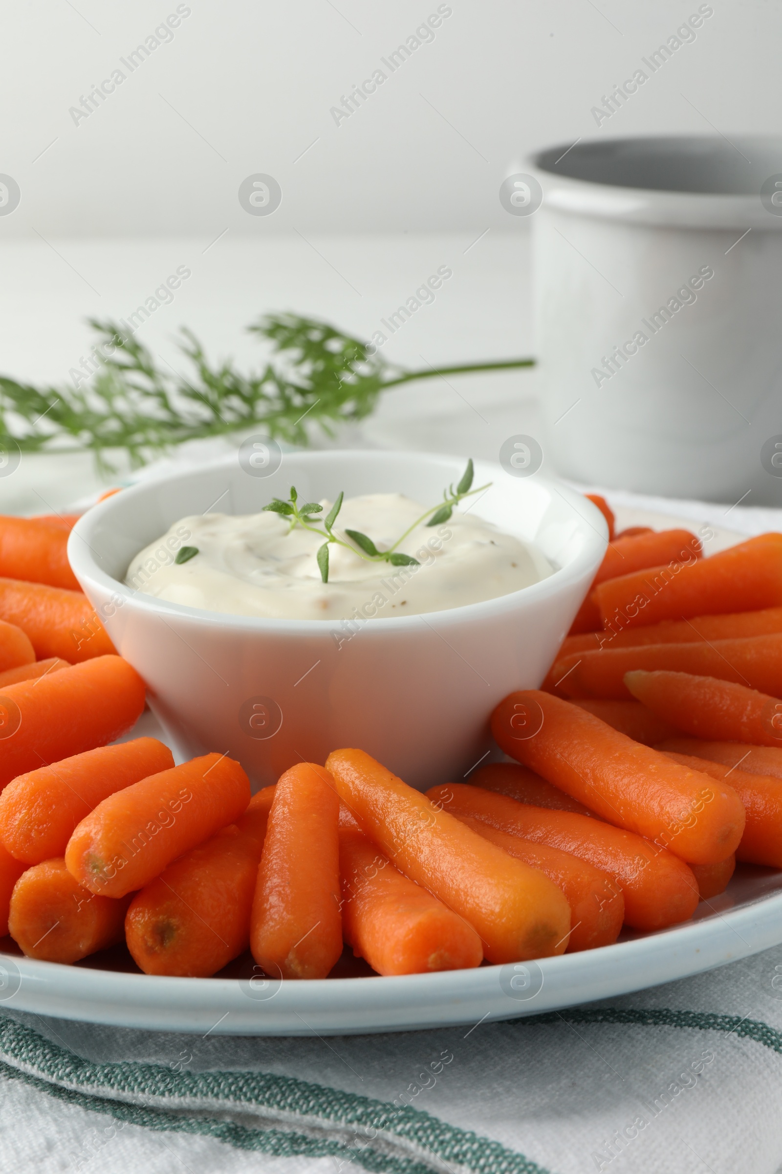 Baby carrots, sauce and green leaf on table, closeup Photo of Baby carrots, sauce and green leaf on table, closeup