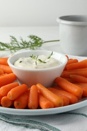 Photo of Baby carrots, sauce and green leaf on table, closeup