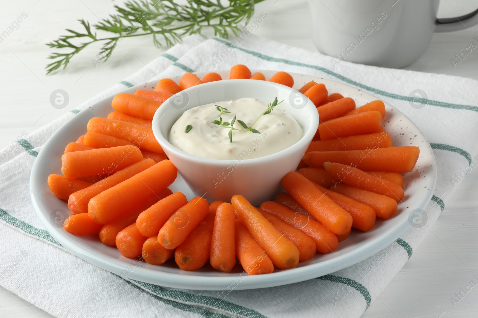 Photo of Baby carrots, sauce and green leaf on white wooden table