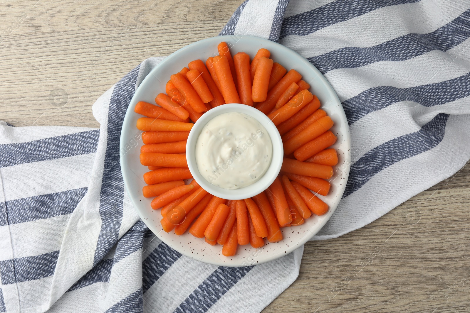 Photo of Baby carrots and sauce on wooden table, top view