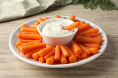 Baby carrots and sauce on wooden table