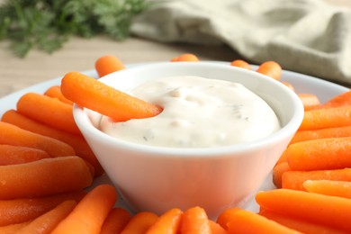 Photo of Baby carrots and sauce on table, closeup