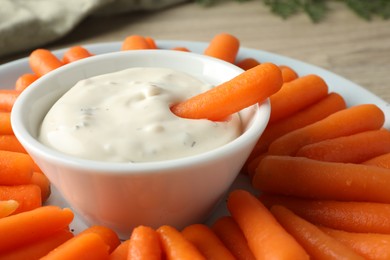 Baby carrots and sauce on table, closeup