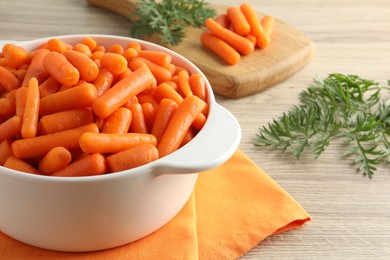 Baby carrots in pot and green leaves on wooden table