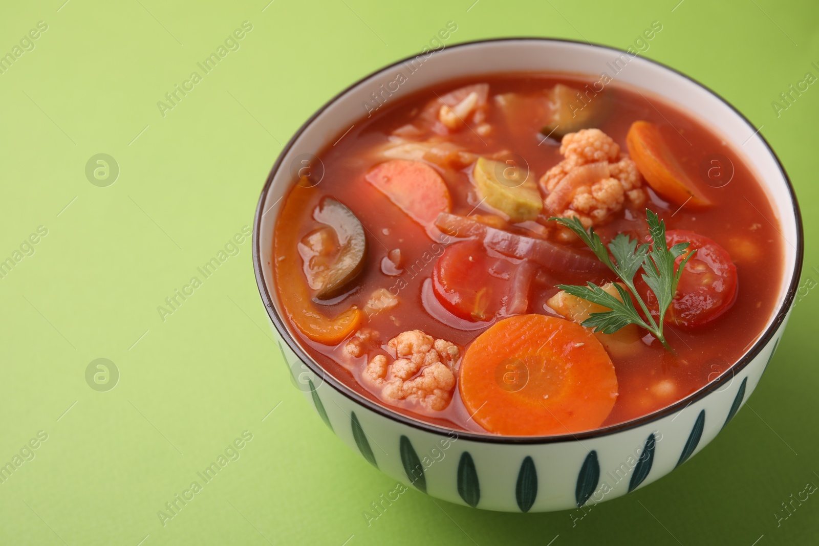 Photo of Tasty homemade stew with vegetables on light green table, closeup. Space for text