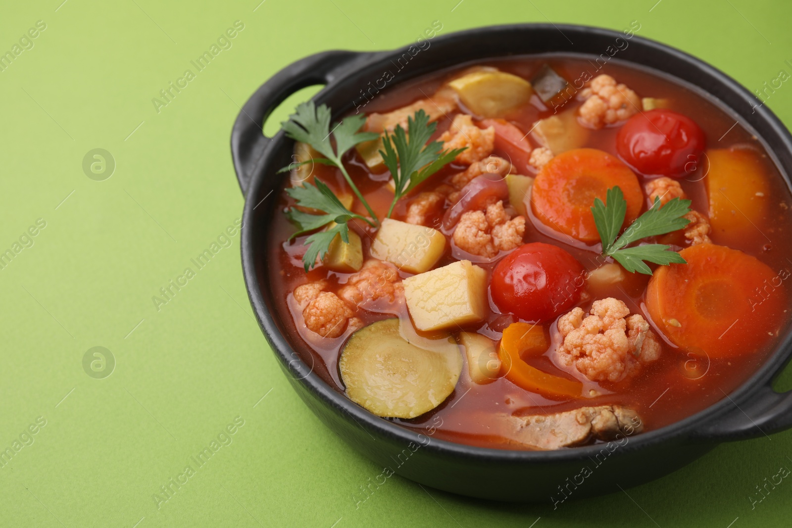 Photo of Tasty homemade stew with vegetables on light green table, closeup. Space for text