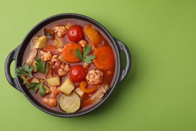 Photo of Tasty homemade stew with vegetables on light green table, top view. Space for text