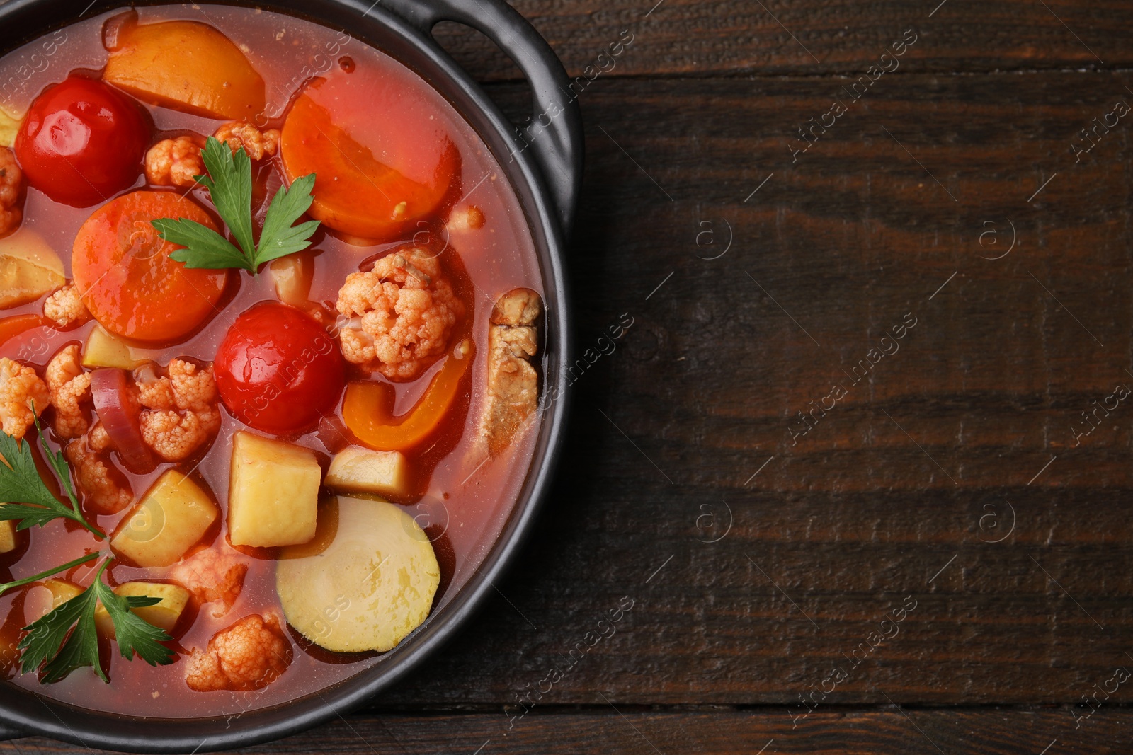 Photo of Tasty homemade stew with vegetables on wooden table, top view. Space for text