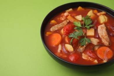 Photo of Tasty homemade stew with vegetables on light green table, closeup. Space for text