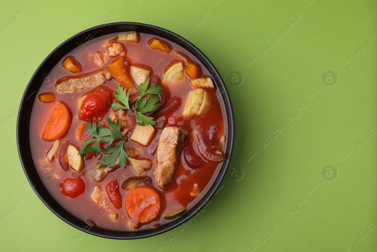 Photo of Tasty homemade stew with vegetables on light green table, top view. Space for text