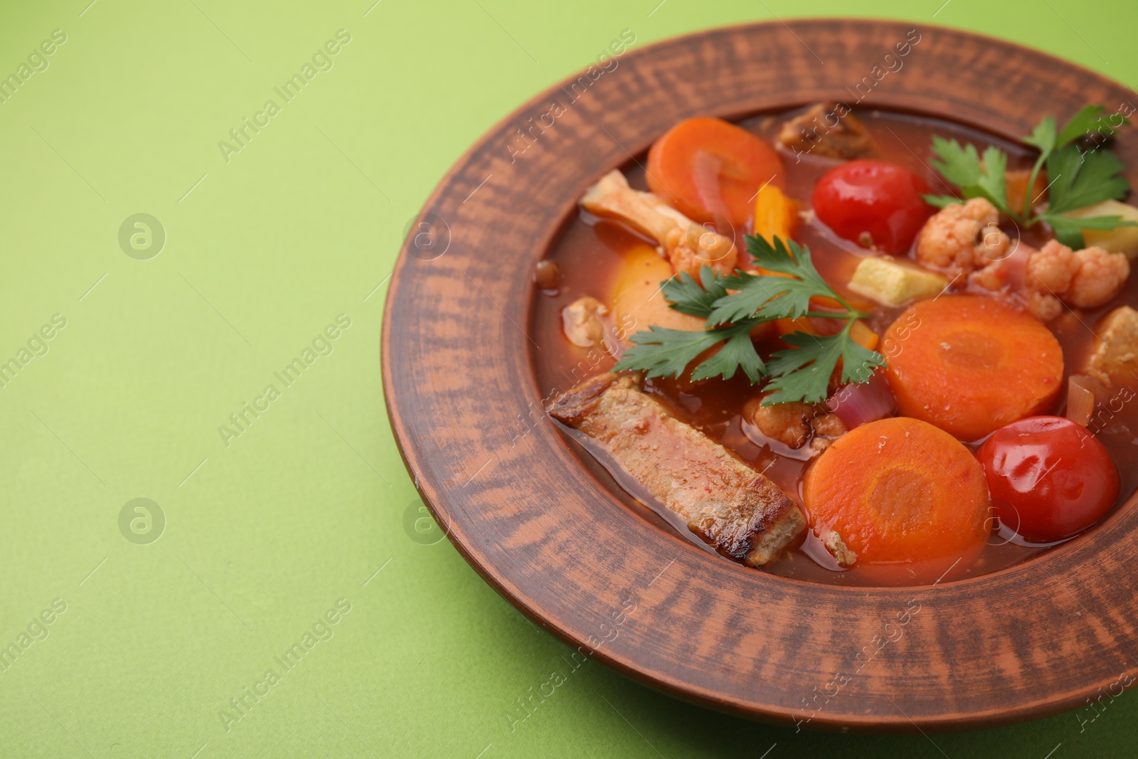 Photo of Tasty homemade stew with vegetables on light green table, closeup. Space for text