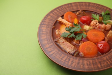 Tasty homemade stew with vegetables on light green table, closeup. Space for text