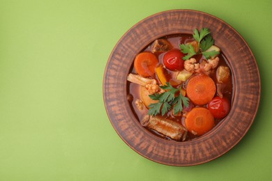 Tasty homemade stew with vegetables on light green table, top view. Space for text