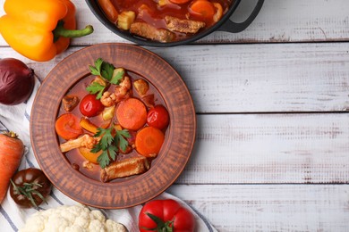 Tasty homemade stew with vegetables on white wooden table, flat lay. Space for text