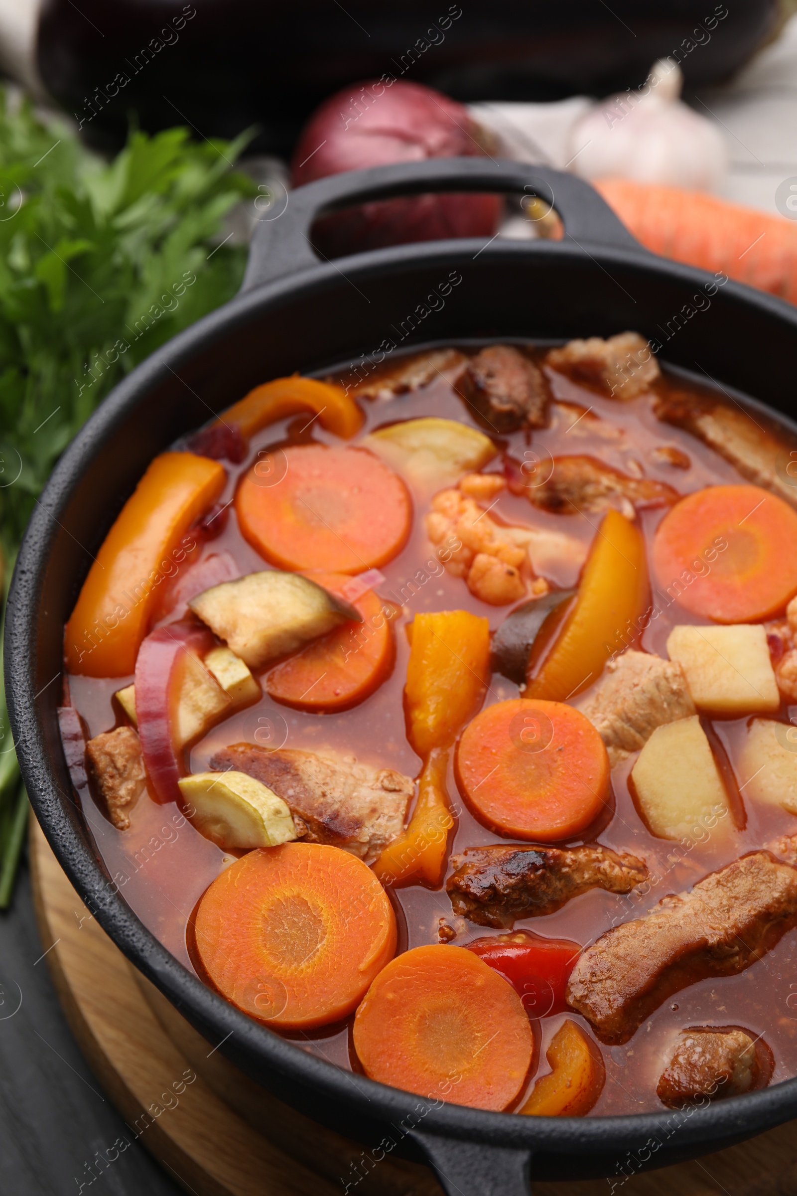 Photo of Tasty homemade stew with vegetables on grey wooden table, closeup