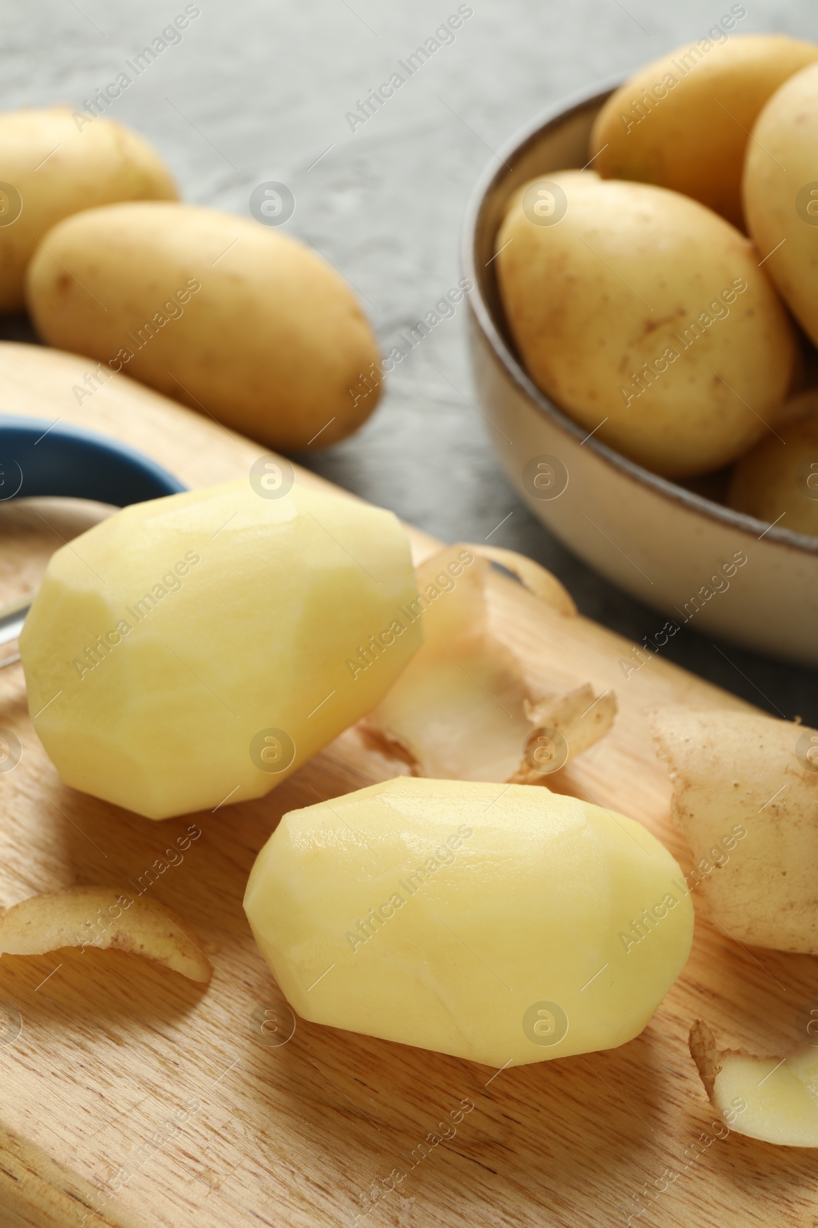 Photo of Fresh raw potatoes and peeler on table, closeup