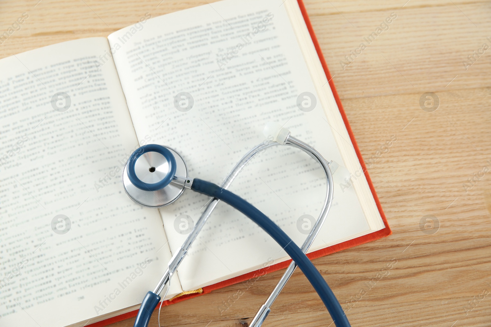 Photo of One new medical stethoscope on wooden table, top view