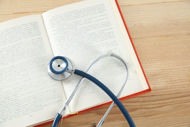 Photo of One new medical stethoscope on wooden table, top view