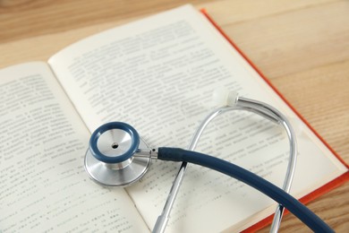 Photo of One new medical stethoscope on wooden table, closeup