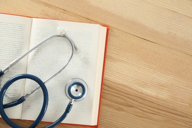 Photo of One new medical stethoscope on wooden table, top view. Space for text