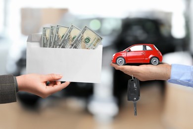 Woman giving money to seller in exchange for car key in shop, closeup. Buying auto