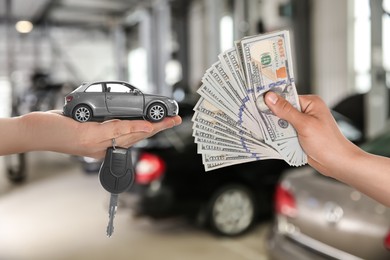 Man giving money to seller in exchange for car key in shop, closeup. Buying auto