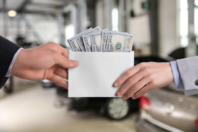 Image of Man giving money to seller in automotive shop, closeup. Buying car