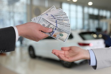 Image of Man giving money to seller in automotive shop, closeup. Buying car