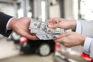 Image of Woman giving money to seller in automotive shop, closeup. Buying car