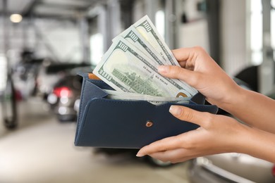 Woman taking money from wallet in automotive shop, closeup. Buying car