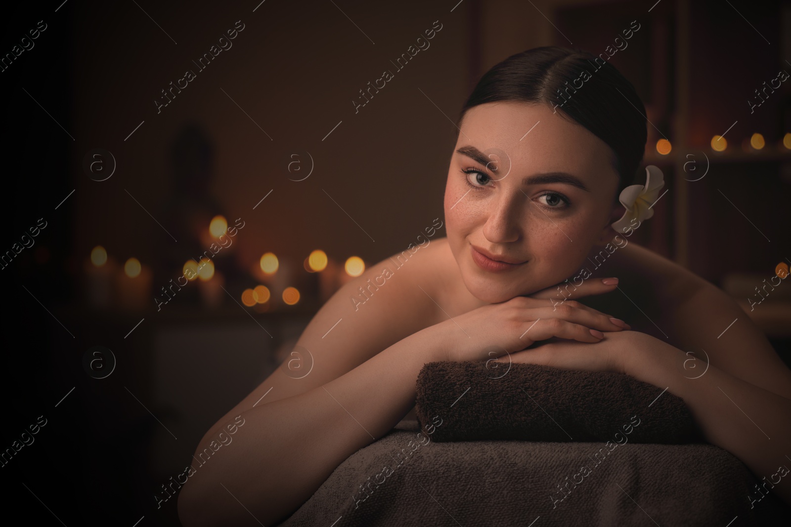 Image of Beautiful young woman lying on massage table in salon, space for text